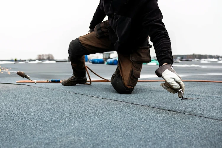 flat roofing systems Man repairing flat roof using felt